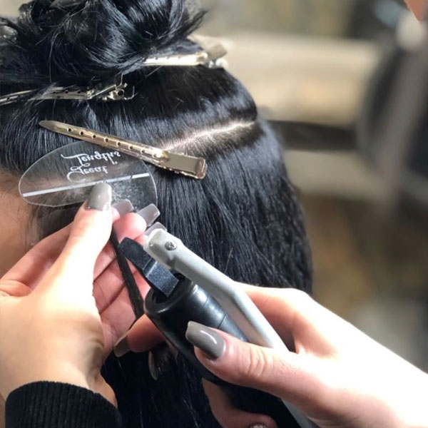 Hair stylist in Wrexham applying extensions